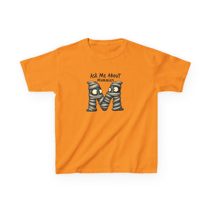 Kids history-themed shirt with “Ask Me About Mummies” design featuring cartoon mummy lettering on a Gildan 5000B Heavy Cotton Tee. Tennessee Orange