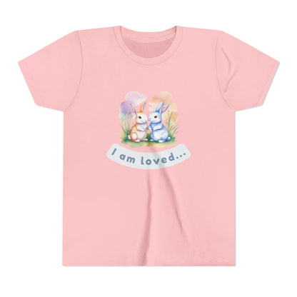 Pink t-shirt with cartoon bunnies and 'I am loved' text on a white background