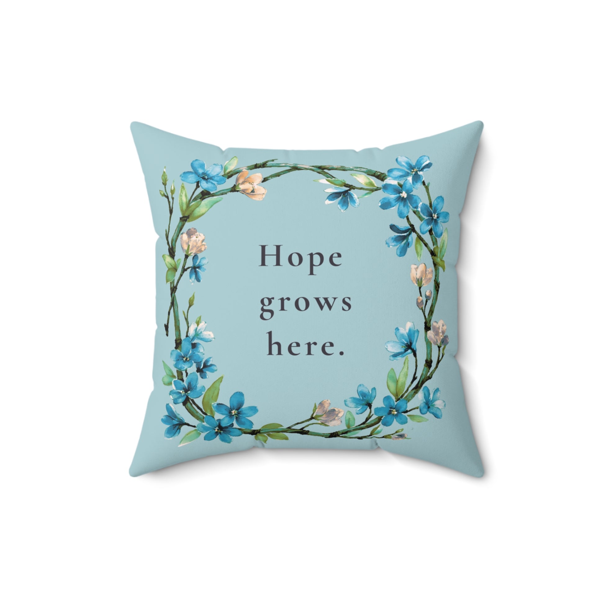 Decorative pillow with floral design and 'Hope grows here' text on a light blue background