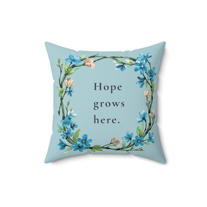 Decorative pillow with floral design and 'Hope grows here' text on a light blue background
