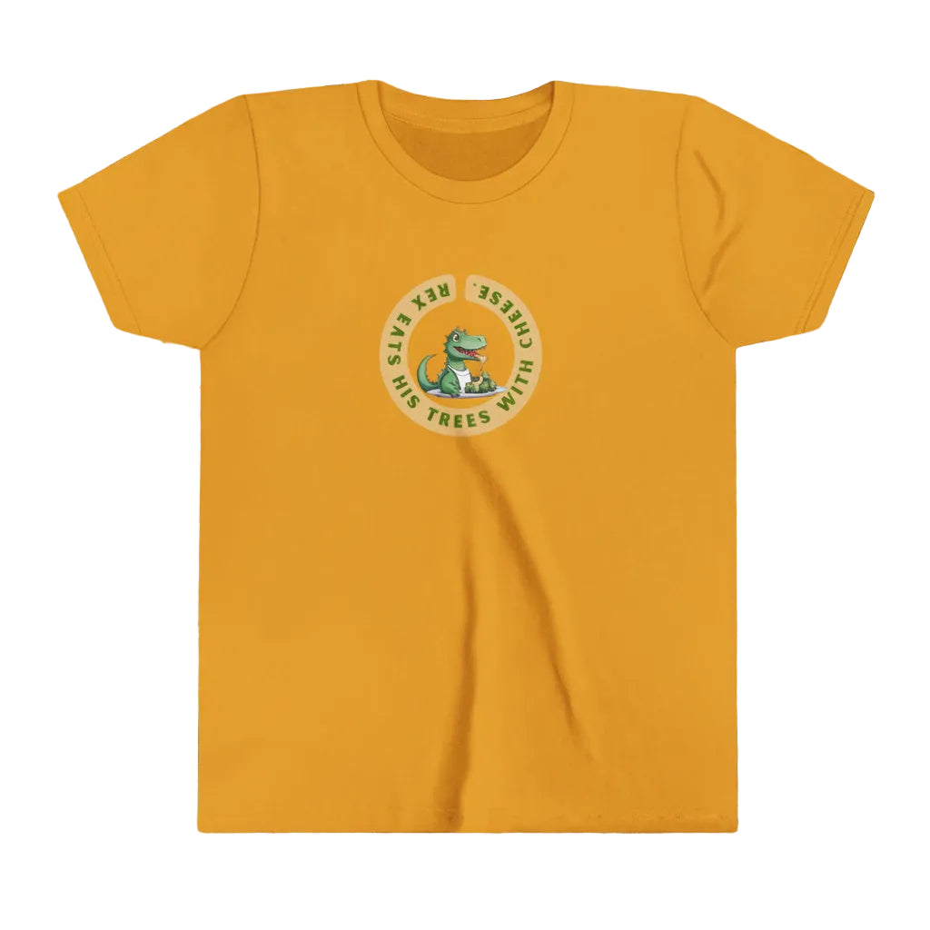 A mustard yellow short-sleeve t-shirt with a circular graphic on the chest featuring a green cartoon dinosaur and the text 'Rex eats his trees with cheese. The backgorudn is grated cheese and broccoli florettes