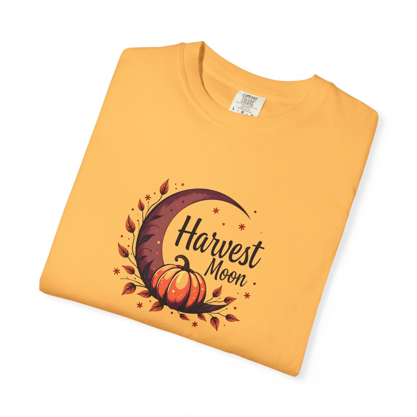 A folded citrus orange t-shirt with a 'Harvest Moon' graphic featuring a crescent moon, autumn leaves, a pumpkin, and stars, displayed on a clean white background.