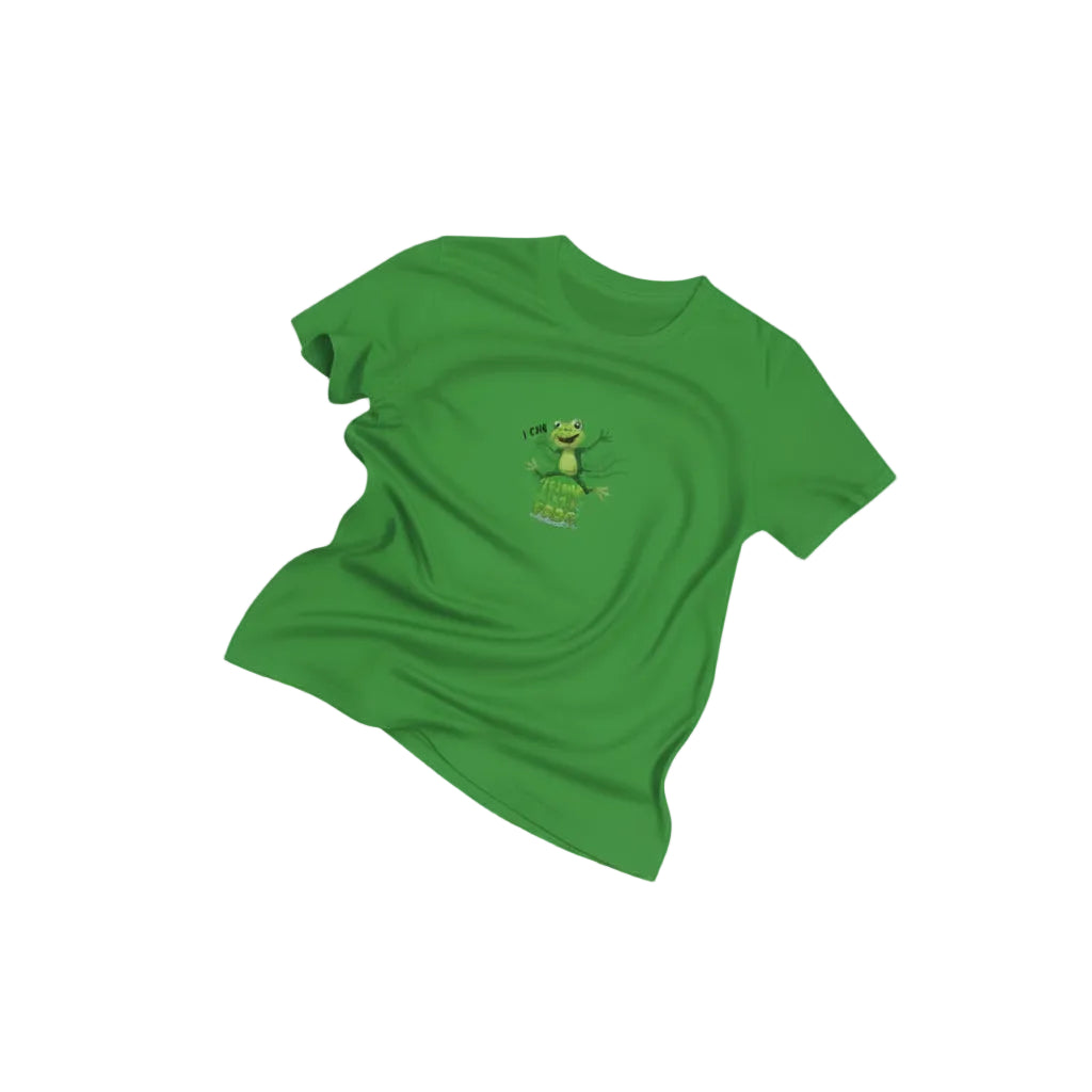 A green short-sleeve t-shirt with a small frog graphic on the chest, displayed on a light cream background decorated with cartoon frogs and orange scribbles.Text on shirt says, "I can jump like a frog."