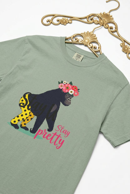 “Girl‑Girl™ gorilla wearing a flower crown and patterned shorts on a bay unisex tee with the phrase ‘Stay Pretty.’”