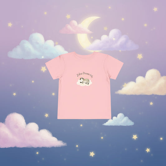 Pink t-shirt with a zebra graphic and text on a white background. Toddler t-shirt with a sleeping watercolor zebra curled on a cloud and text reading ‘Zebra Dreams.’ Not intended for sleepwear.