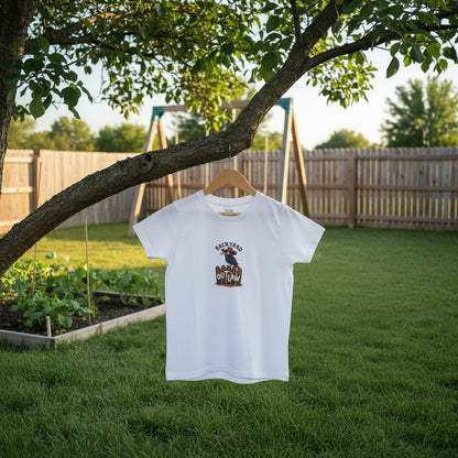 A white short-sleeve crewneck t-shirt featuring a graphic print of a toucan wearing a cowboy hat on a wooden fence with the words 'BACKYARD OUTLAW'. AI-generated from the imagination of Malika Bourne Legacy.