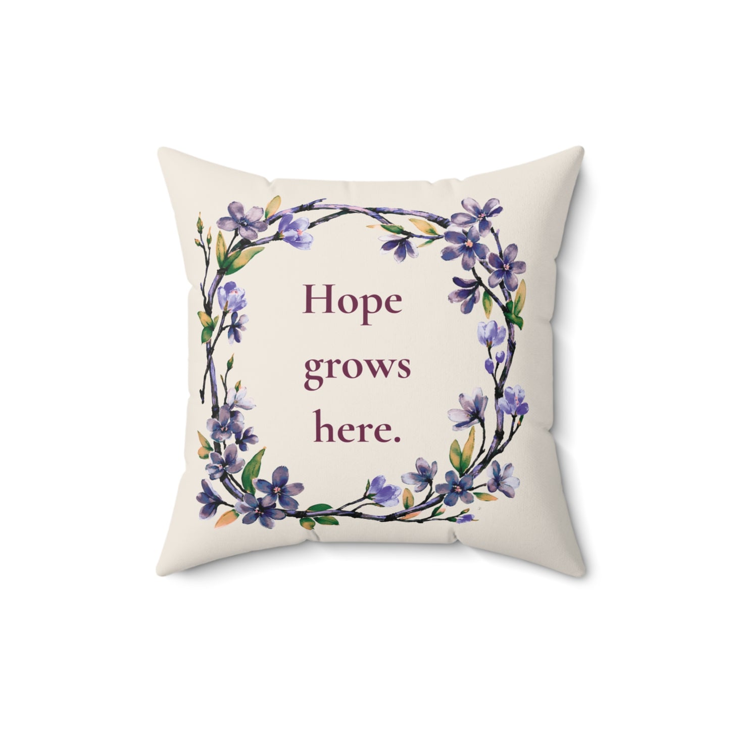Decorative pillow with floral design and 'Hope grows here' text on a white background