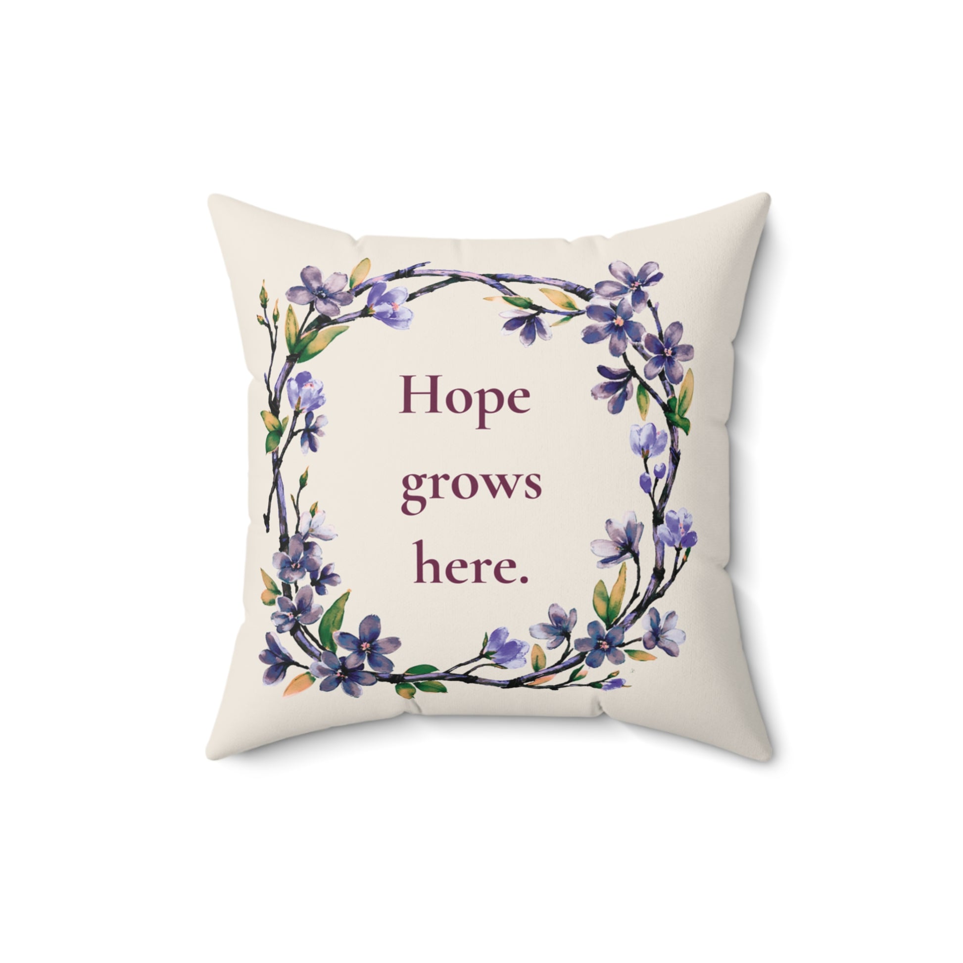 Decorative pillow with floral design and 'Hope grows here' text on a white background