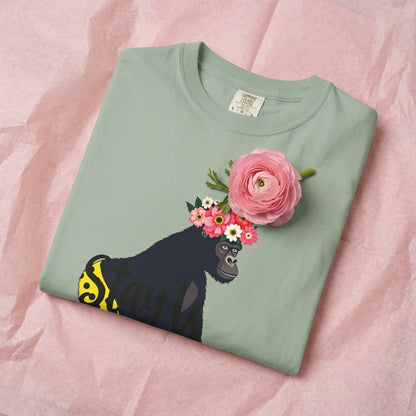Folded Bay “Girl‑Girl™ gorilla wearing a flower crown and patterned shorts on a white unisex tee with the phrase ‘Stay Pretty.’” Lys on pink tissue paper. One flower.
