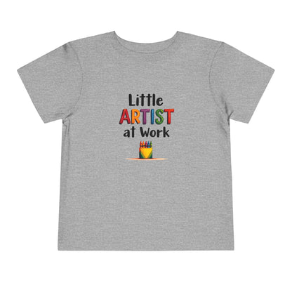 A heather gray short-sleeve toddler's t-shirt with a colorful graphic on the chest that reads 'Little ARTIST at Work' above a small crayon box illustration, shown on a plain white background.