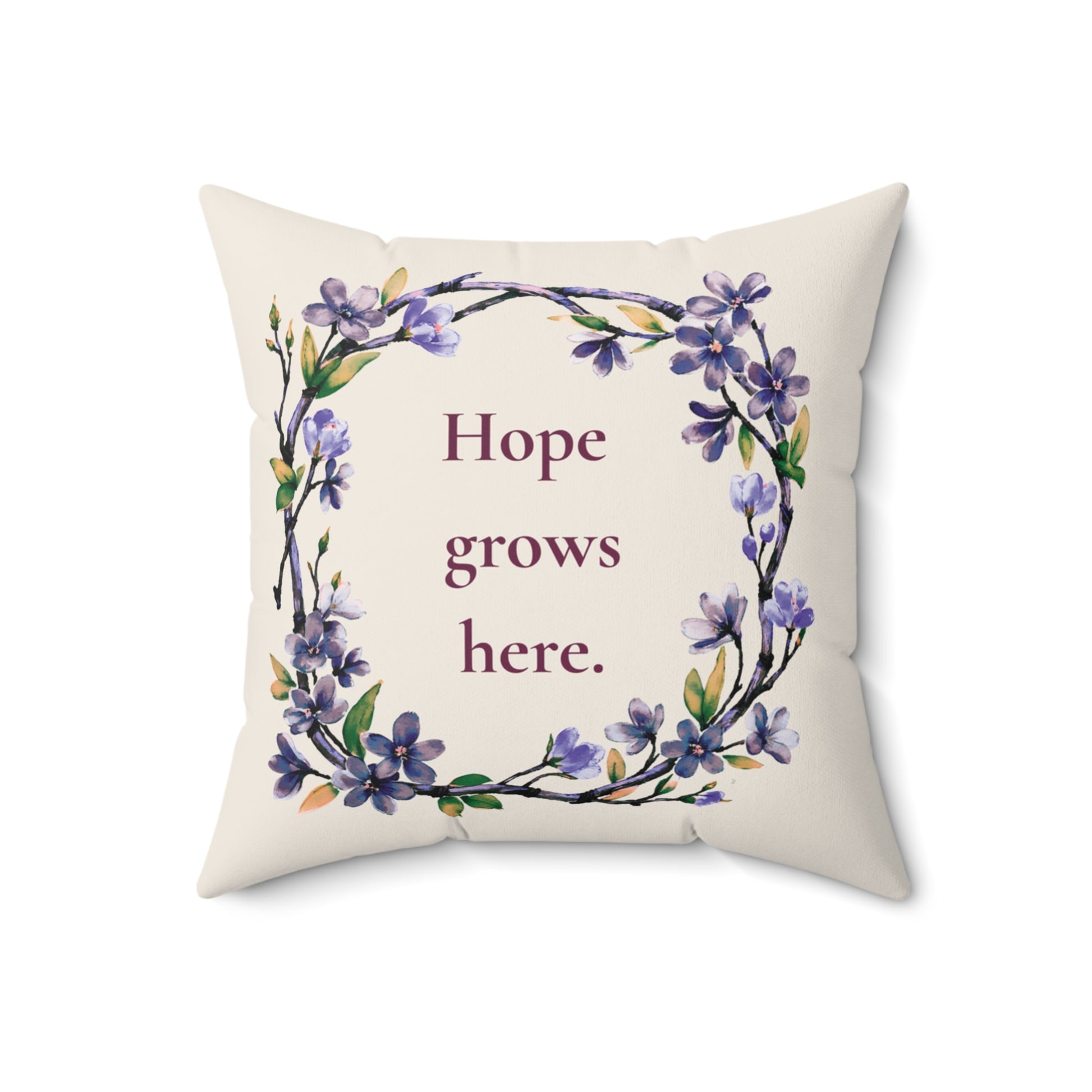 Decorative pillow with floral design and 'Hope grows here' text on a white background