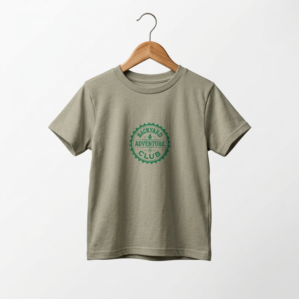 Toddler adventure tee with Backyard Adventure Club emblem in green on a Heather Stone  tee. On a wooden hanger.