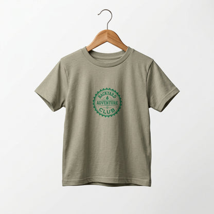 Toddler adventure tee with Backyard Adventure Club emblem in green on a Heather Stone  tee. On a wooden hanger.