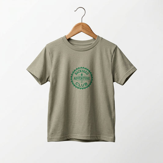 Toddler adventure tee with Backyard Adventure Club emblem in green on a Heather Stone  tee. On a wooden hanger.