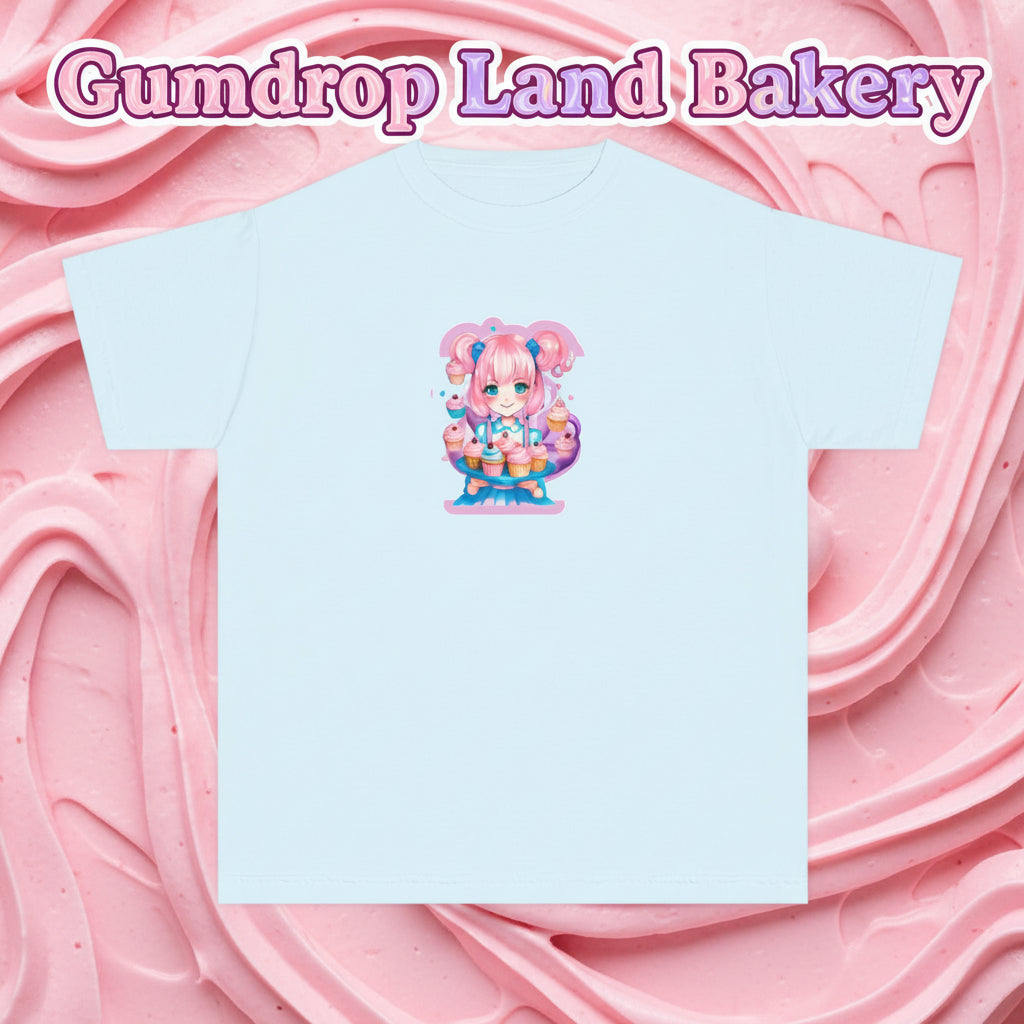 A light blue short-sleeve crewneck t-shirt featuring a colorful graphic print of a cute anime-style character with pink hair and a cake, centered on the chest.