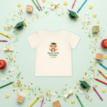 Toddler T‑shirt with a cheerful monkey wearing a graduation cap and holding a diploma, with the text ‘Smart Little Primate 2026" on the front of the natural colored tee.