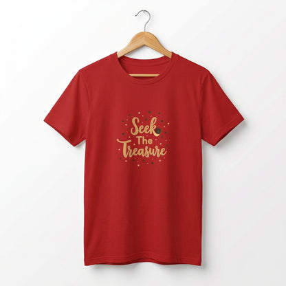 Kids red T‑shirt with golden “Seek the Treasure” lettering surrounded by small star accents. Shirt on a hanger.