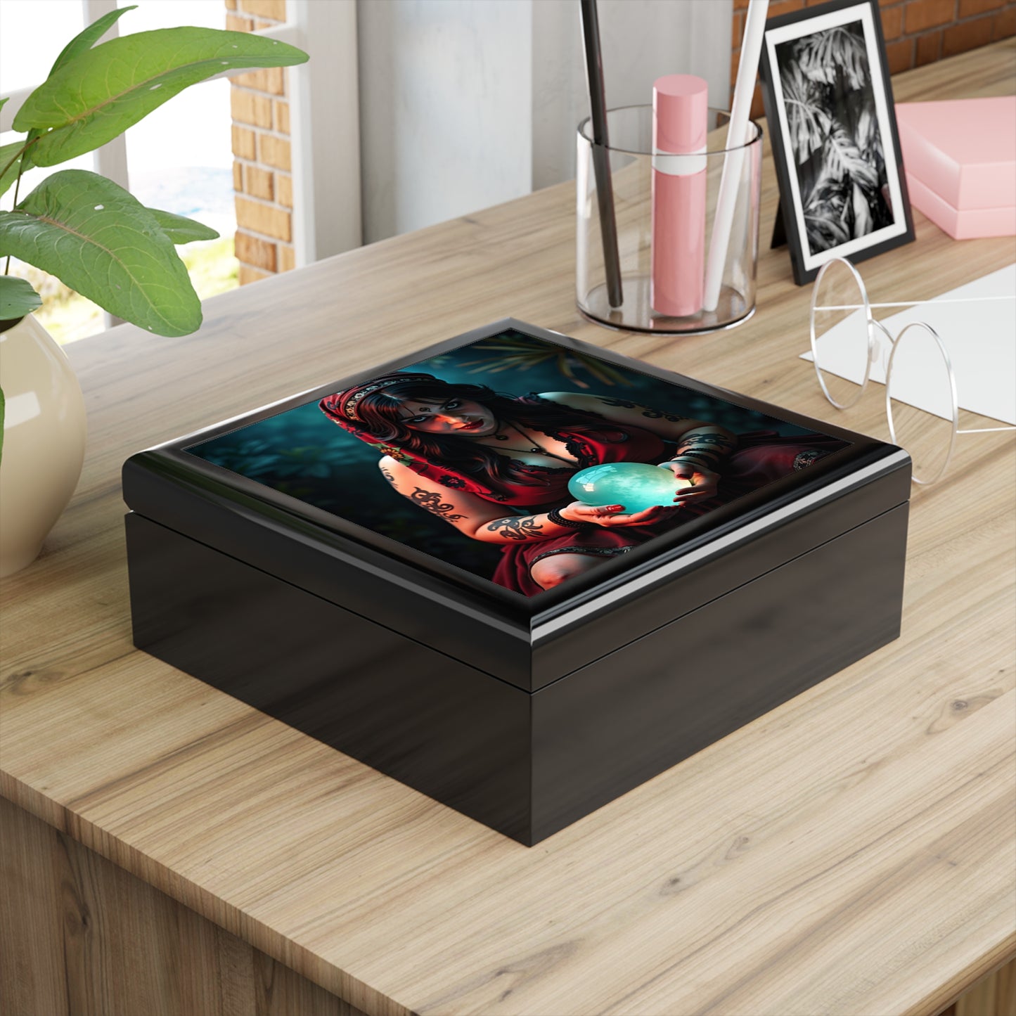 Black square wooden box with a colorful design of a woman holding a blue globe on a wooden surface