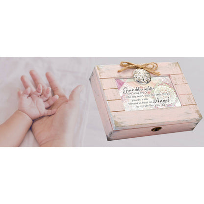 Wooden box with a decorative tag and a small figurine, accompanied by a hand holding a baby's hand.