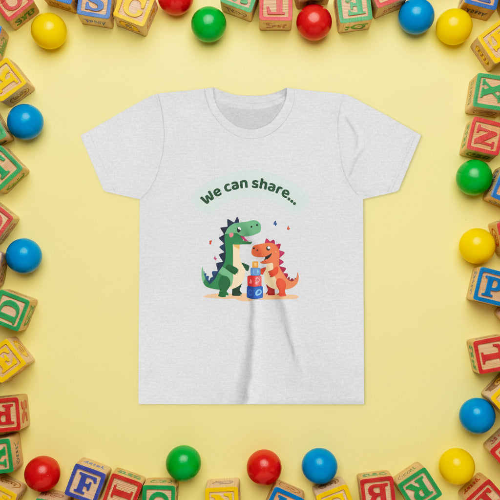 White t-shirt with cartoon dinosaurs and text 'We can share' on a yellow background and border of wooden blocks and balls.