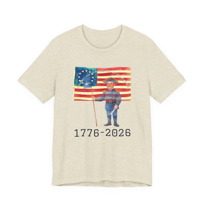 Beige t-shirt with a graphic of a person holding an American flag and the text '1776-2026' on a white background.