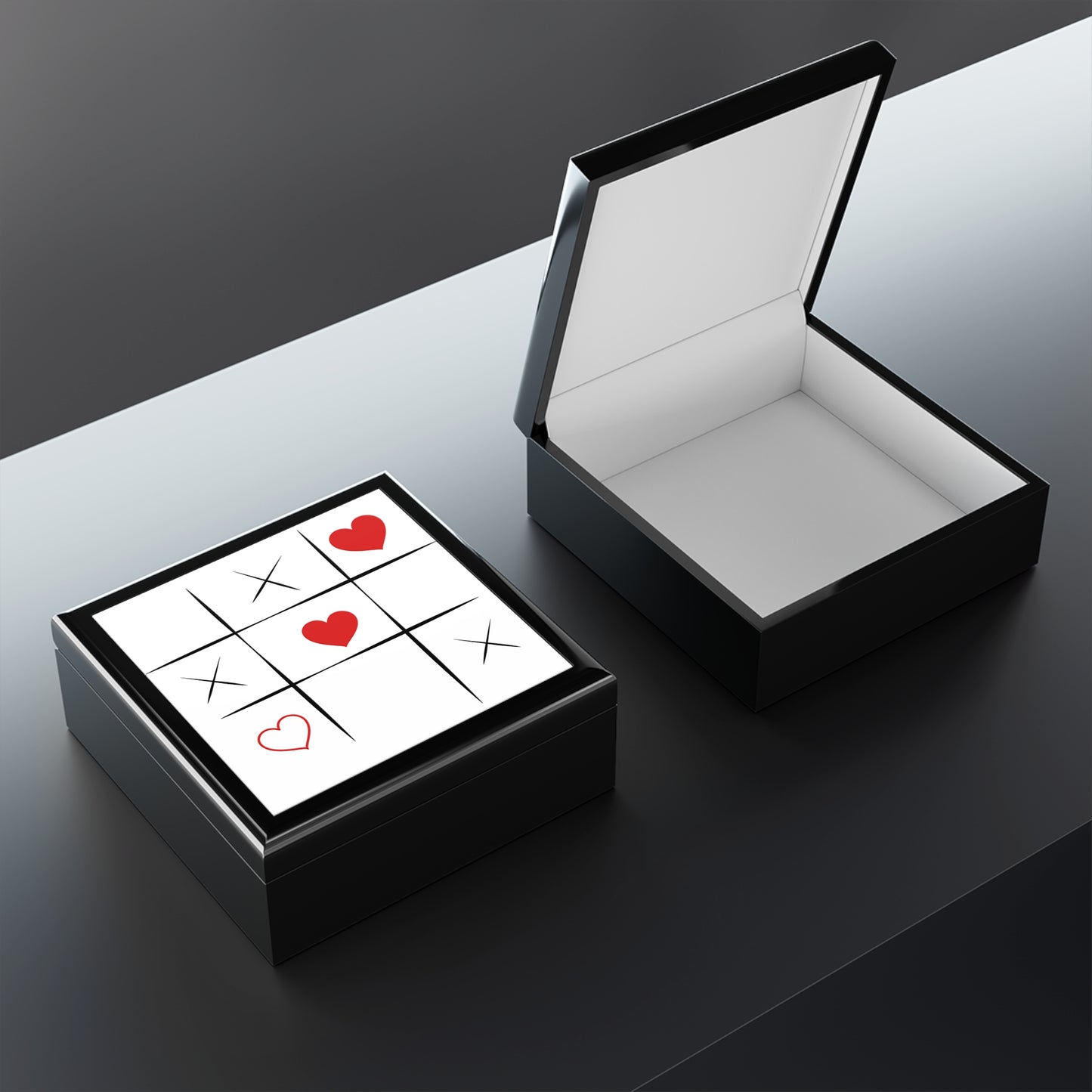 Black jewelry box with a white interior and a small card inside on a dark surface.