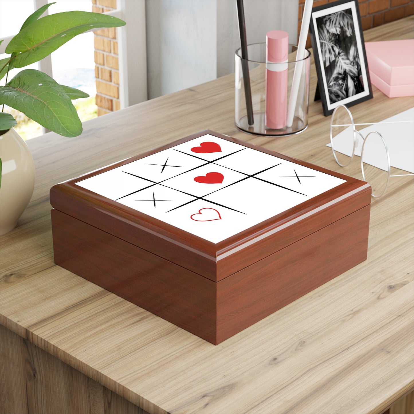 Wooden box with tic-tac-toe design featuring red hearts on a wooden surface.