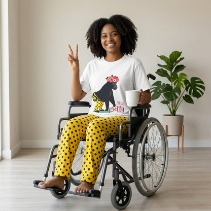 AI model wears the shirt. “Girl‑Girl™ gorilla wearing a flower crown and patterned shorts on a white unisex tee with the phrase ‘Stay Pretty.’” AI model sits in a wheelchair and wears AI-generated pants that match what the tee gorilla character is wearing: yellow pants with block dots.