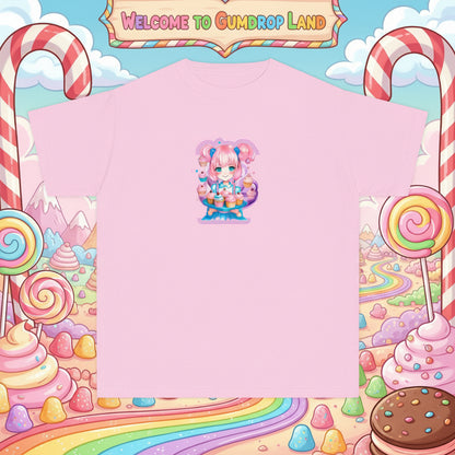 A light pink short-sleeve crewneck t-shirt featuring a colorful anime-style graphic of a character with pink hair and a cake on the center chest, displayed against a playful candy-land- like pastel background. A sign read, "Welcom to Gumdrop Land" . Malika Bourtne Legacy design