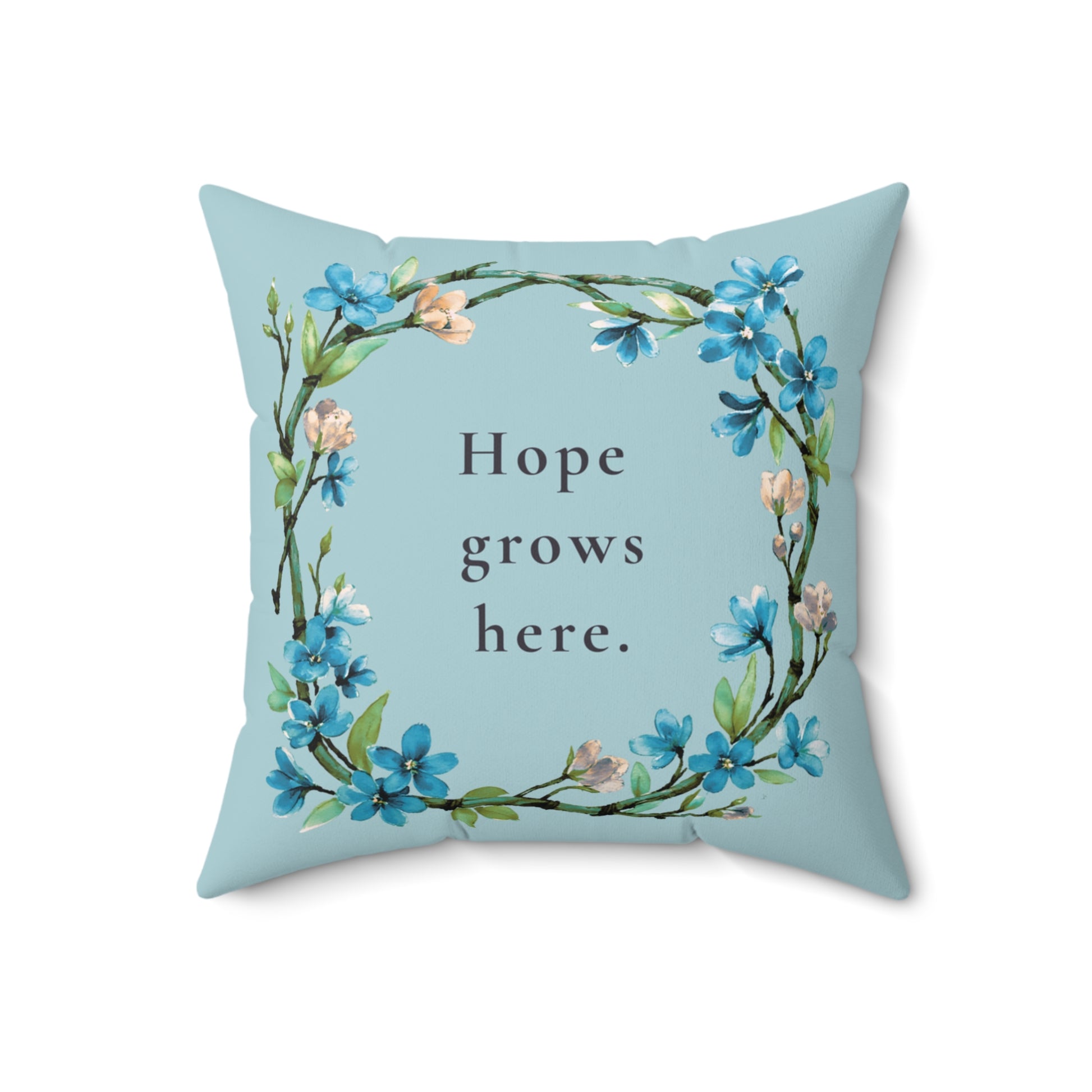 Decorative pillow with floral design and 'Hope grows here' text on a light blue background