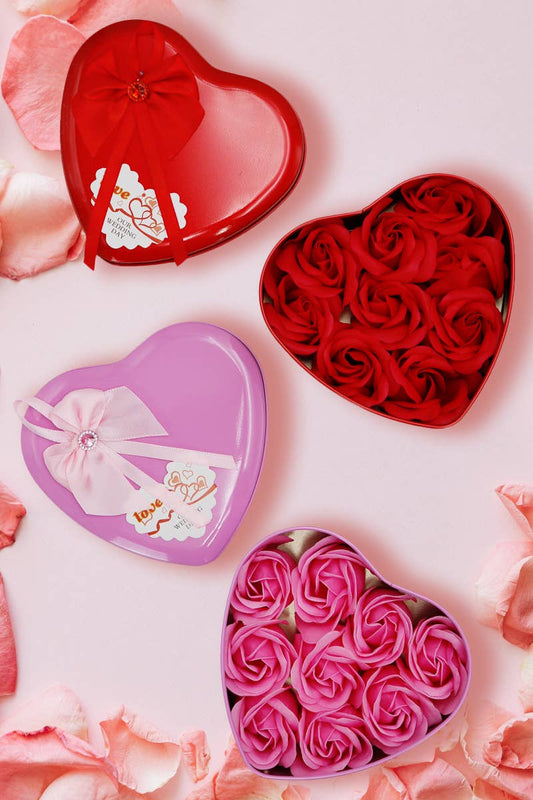 Heart-shaped boxes filled with red and pink roses on a light pink background with flower petals.