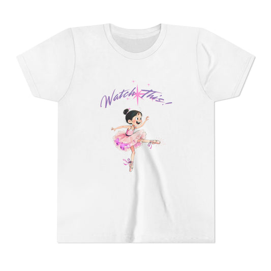 A white short-sleeve crewneck t-shirt featuring a cartoon illustration of a young ballerina in a pink tutu with the text 'Watch This!' in purple script above her, displayed on a clean white background. AI