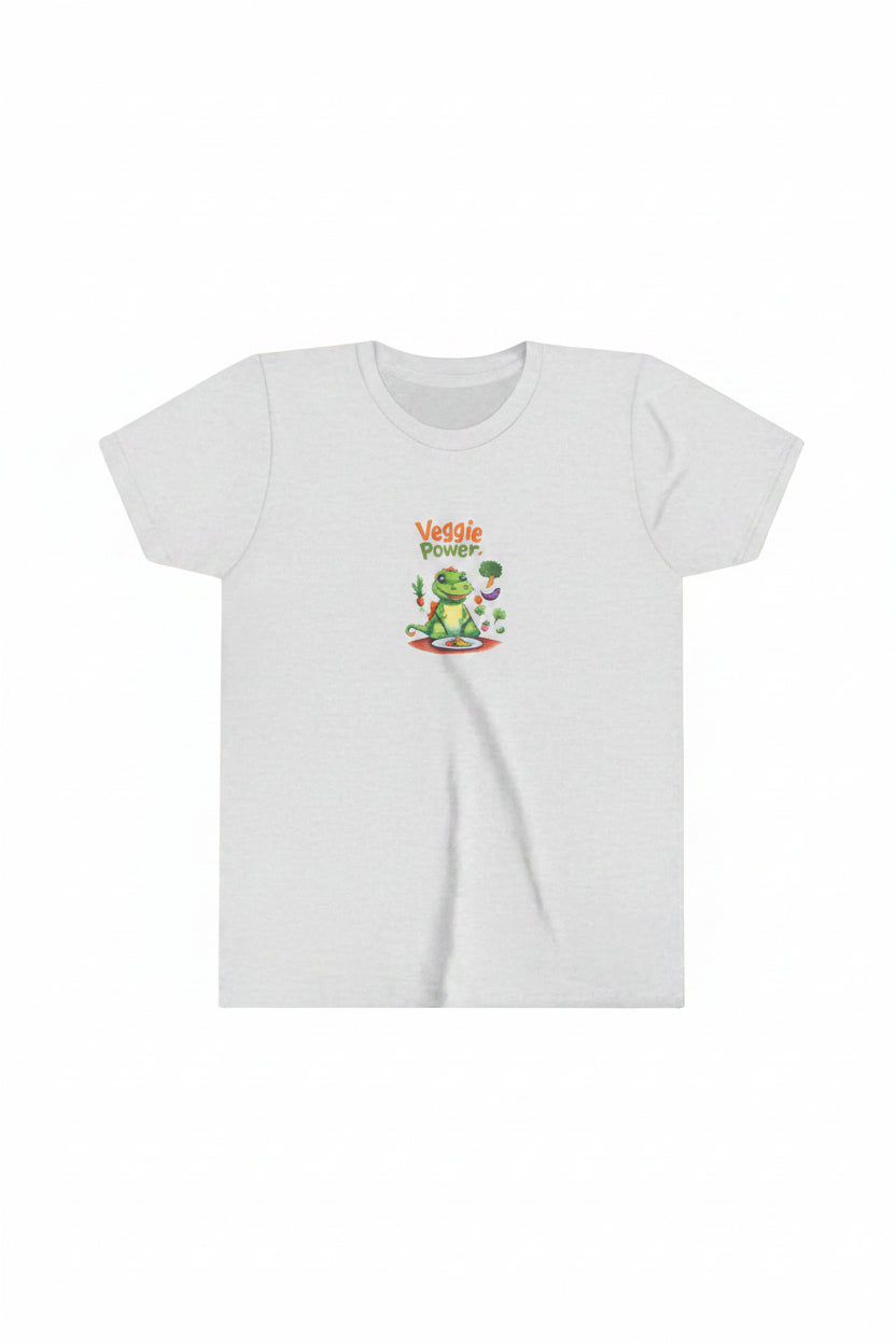 A light heather gray short-sleeve t-shirt with a colorful graphic on the chest. The graphic features a cartoon green dinosaur or aligator holding a carrot and broccoli, sitting at a table with a plate of veggies. Shirt with the text 'Veggie Power' above it.
