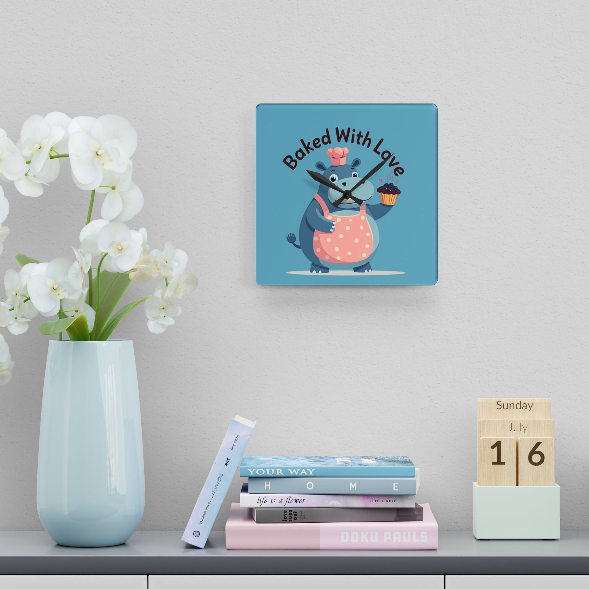 Decorative wall clock with cartoon character and 'Baked With Love' text, placed on a shelf with books and a vase.