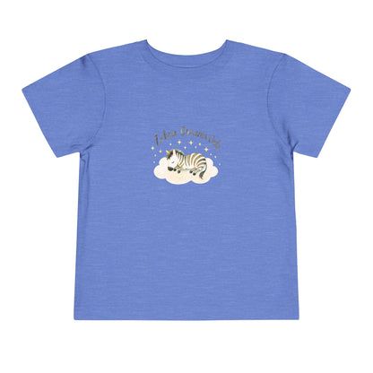 Blue t-shirt with a zebra graphic and text on a white background. Toddler t-shirt with a sleeping watercolor zebra curled on a cloud and text reading ‘Zebra Dreams.’