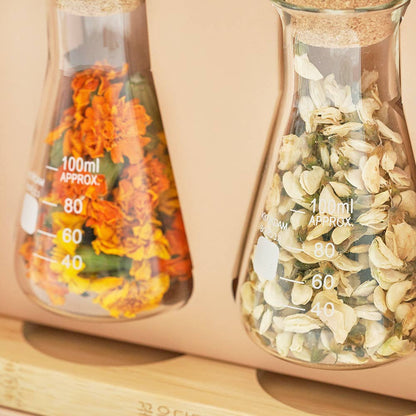 Two glass containers with floral elements on a beige background