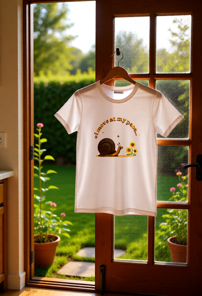 White t-shirt with a snail graphic on a hanger in front of a glass door with a garden view.