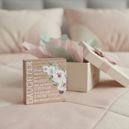 Wooden box lid with floral design and motivational quote on a wooden background. Looks like the featured lid was just unwrapped from gift box.