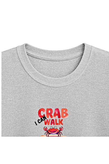 A close-up of a light heather gray t-shirt featuring a graphic print on the chest. The graphic displays the text 'I CAN WALK LIKE A CRAB' in red and orange letters, with 'I CAN' in black script above it, and a cartoon crab illustration underneath.